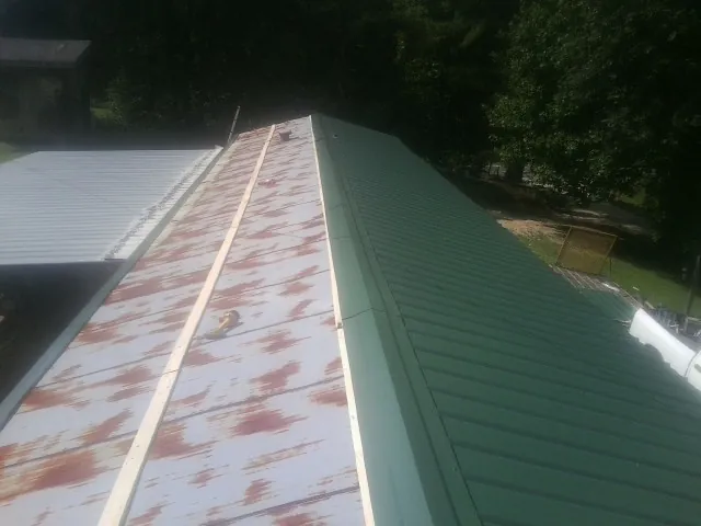 Old rusted panels beside newly installed green metal roofing — Wind Damage Roof Repair by Roofing Brothers in Central Valley