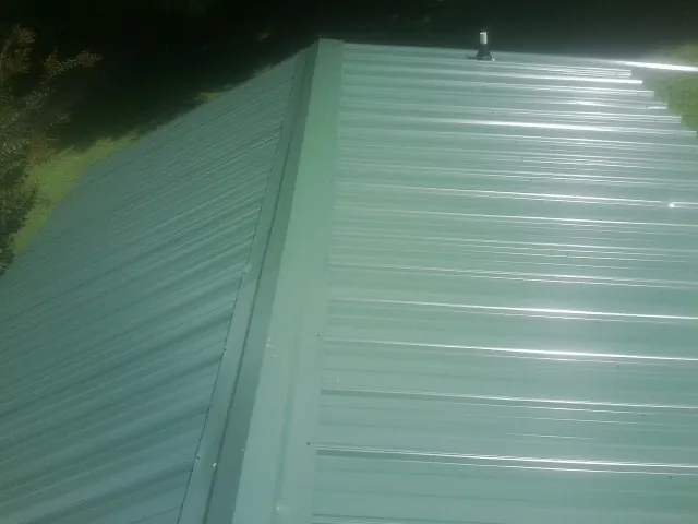 New green metal panels meeting at the ridge of a roof — Flat Roof Repair work by our crew in Central Valley
