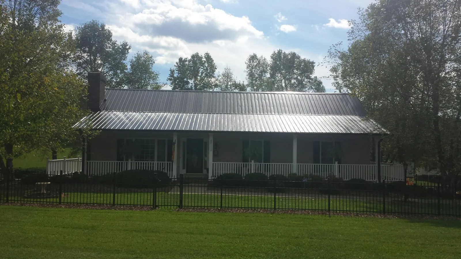 Gray metal roof on a brick ranch with a full width front porch — Gutter Guard Installation work by our crew in Central Valley