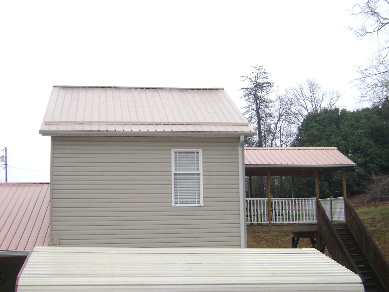 Tan metal roofs on a two story addition and attached porch, from a Roof Replacement job in Central Valley