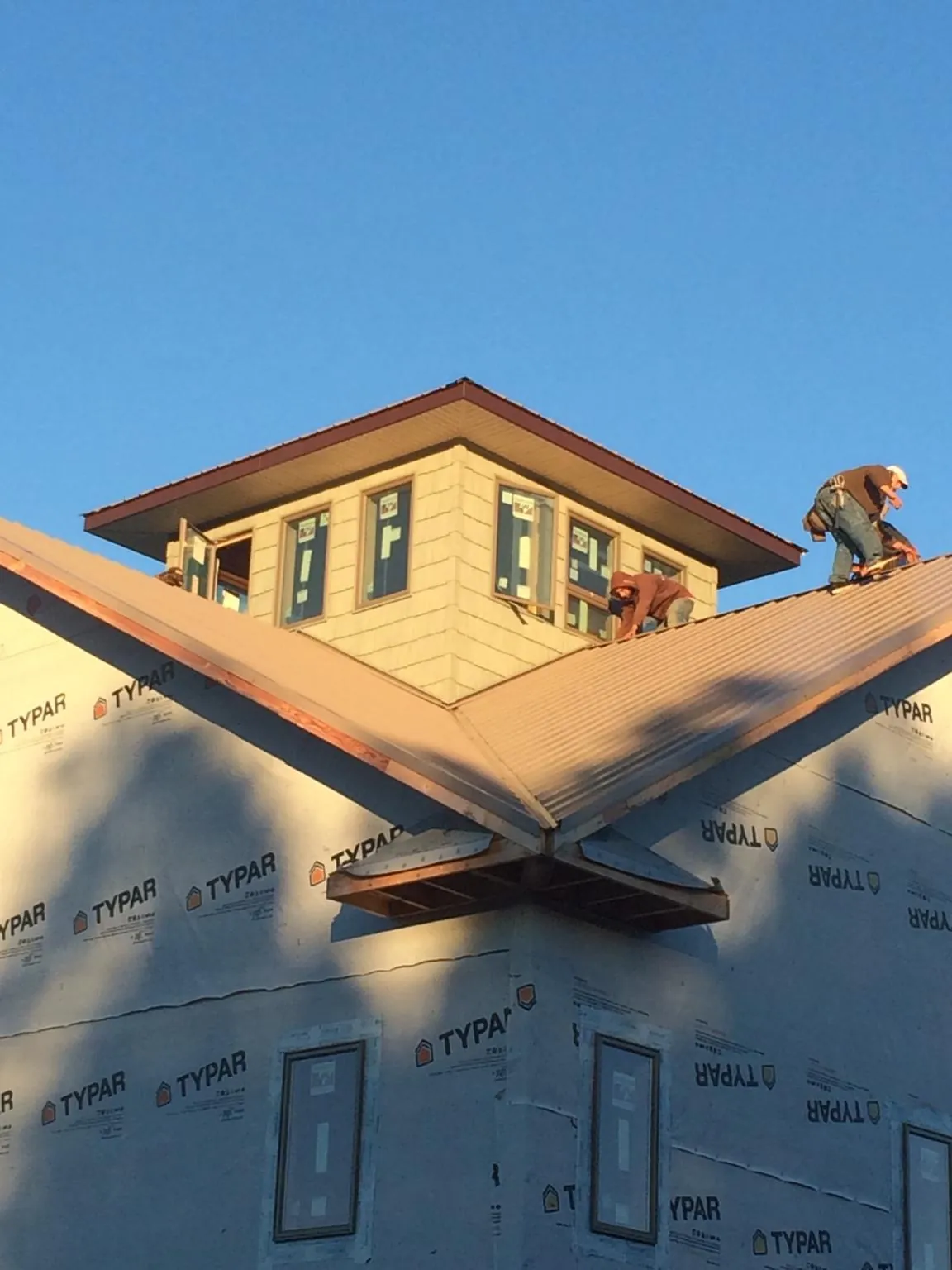 Roofers working around a rooftop cupola on a new metal roof at sunset — Roof Waterproofing in Central Valley by Roofing Brothers